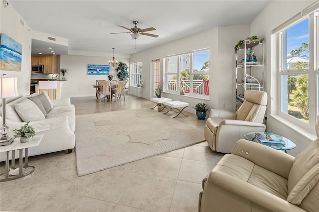 tiled living room featuring ceiling fan with notable chandelier