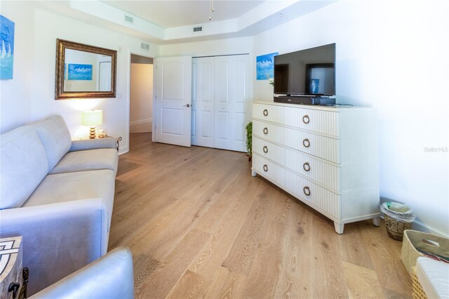 living room with light hardwood / wood-style floors and a tray ceiling