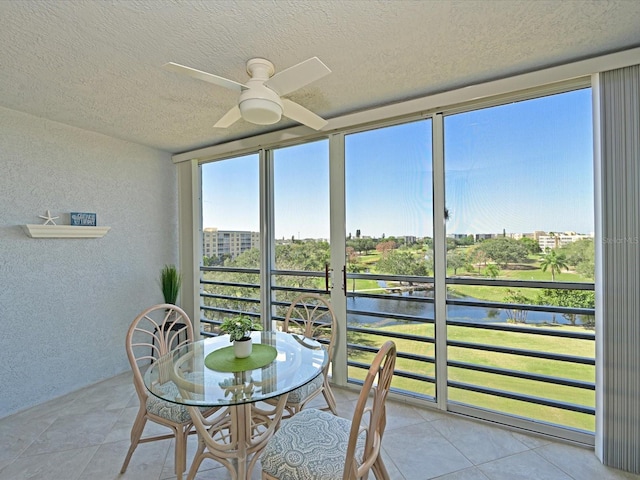 sunroom / solarium with a water view and ceiling fan