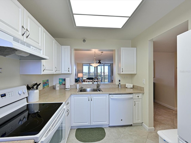 kitchen featuring white appliances, sink, light tile floors, light stone countertops, and white cabinetry