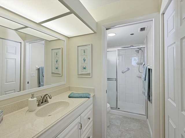 bathroom featuring tile floors, a shower with shower door, vanity with extensive cabinet space, and toilet