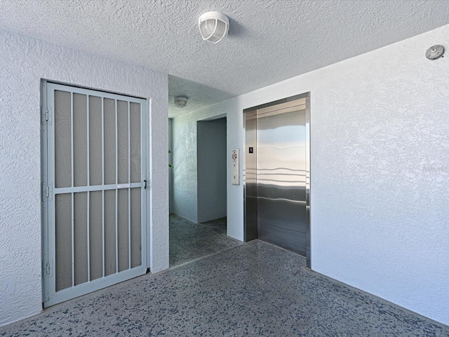 empty room with elevator and a textured ceiling