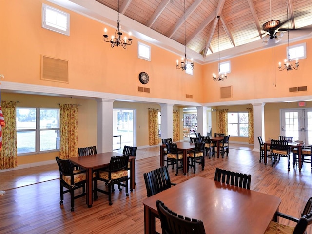 dining space featuring a chandelier, beamed ceiling, wooden ceiling, ornate columns, and high vaulted ceiling