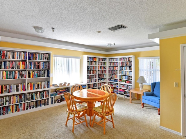 dining area featuring light carpet and a textured ceiling