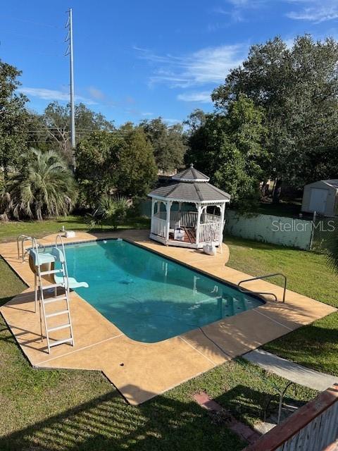 view of pool featuring a gazebo, a diving board, and a lawn