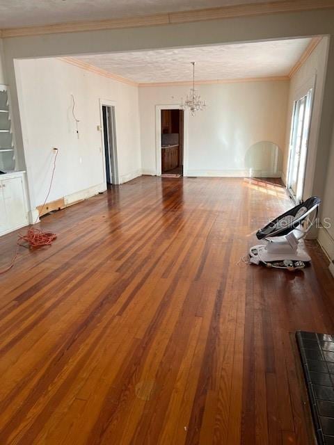 unfurnished living room featuring ornamental molding, wood finished floors, and a chandelier