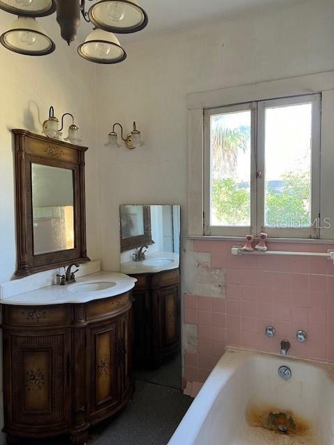 bathroom featuring two vanities, a bathtub, and a sink