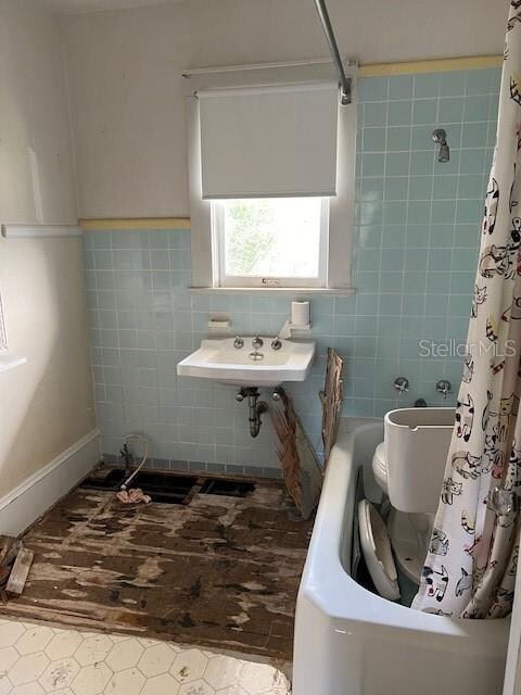 full bathroom featuring a shower with shower curtain, toilet, a bathtub, and a sink