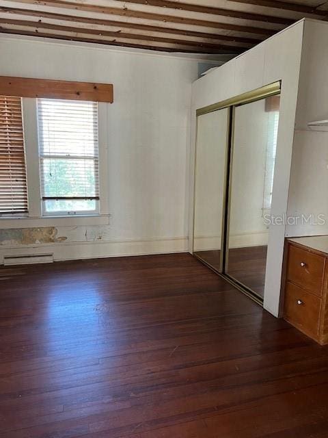 unfurnished bedroom with visible vents, dark wood-style flooring, and a closet