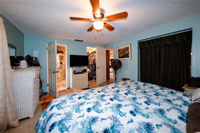 carpeted bedroom with a spacious closet, a textured ceiling, a closet, and ceiling fan