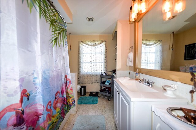 bathroom featuring plenty of natural light, large vanity, and toilet