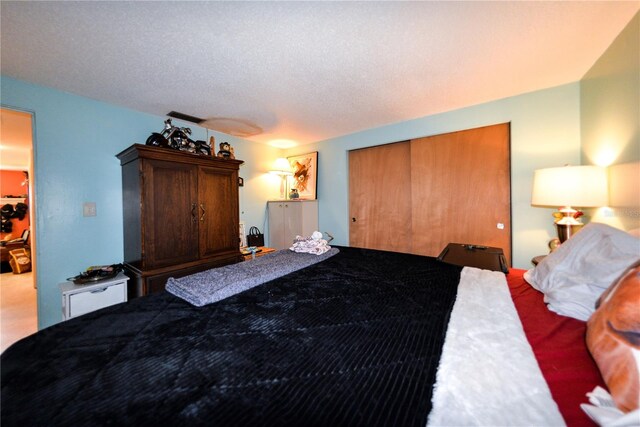 carpeted bedroom featuring a textured ceiling and a closet