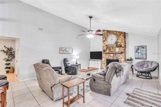 living room featuring light tile flooring, a stone fireplace, ceiling fan, and high vaulted ceiling