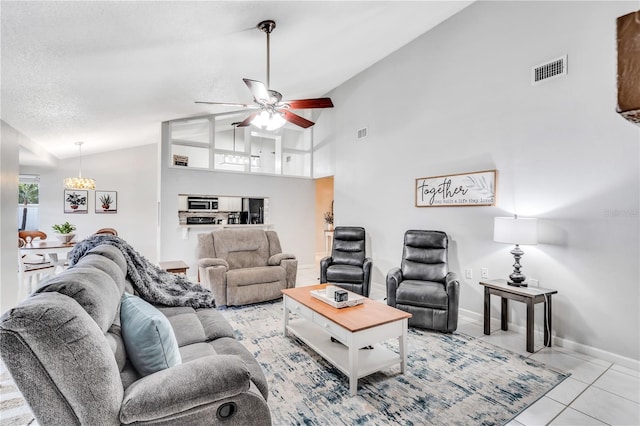 tiled living room featuring high vaulted ceiling, a textured ceiling, and ceiling fan with notable chandelier