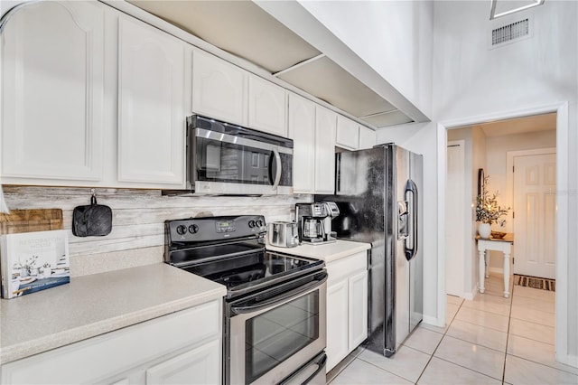 kitchen featuring refrigerator with ice dispenser, range with electric stovetop, white cabinets, backsplash, and light tile flooring