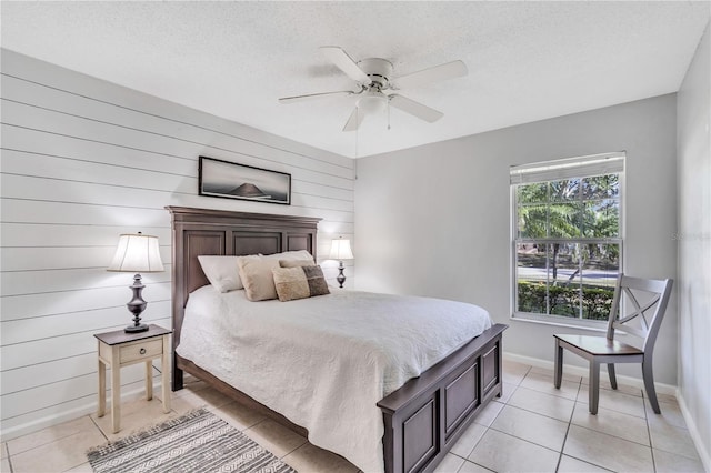 bedroom with wood walls, a textured ceiling, ceiling fan, and light tile floors