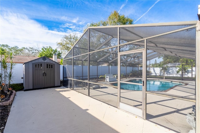 view of swimming pool featuring glass enclosure, a shed, and a patio area