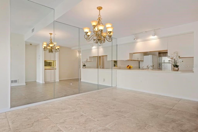 tiled empty room featuring a chandelier and sink