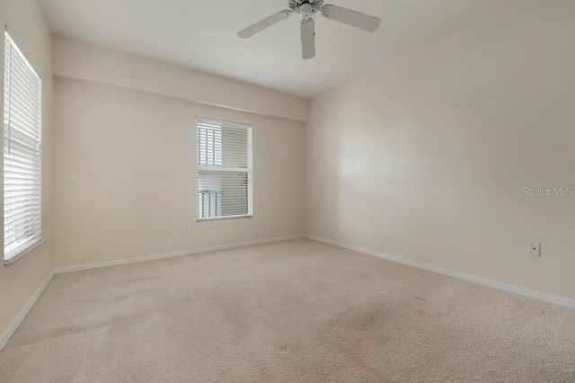 carpeted spare room featuring plenty of natural light and ceiling fan