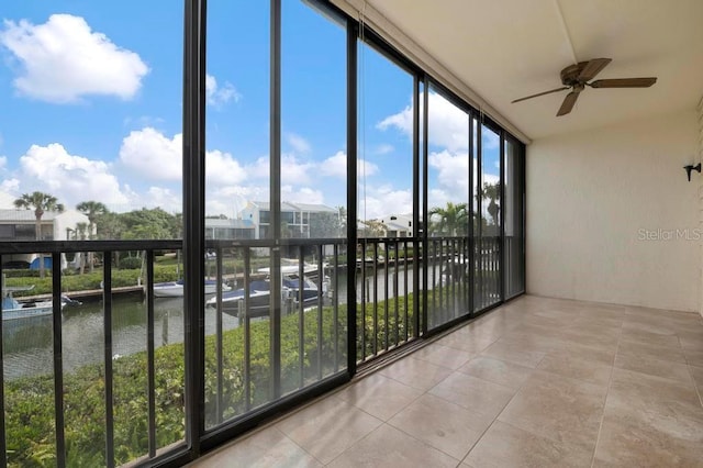 unfurnished sunroom featuring a water view and ceiling fan