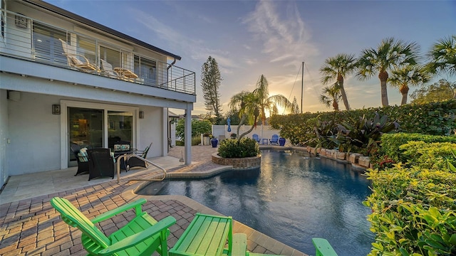 pool at dusk featuring a patio area