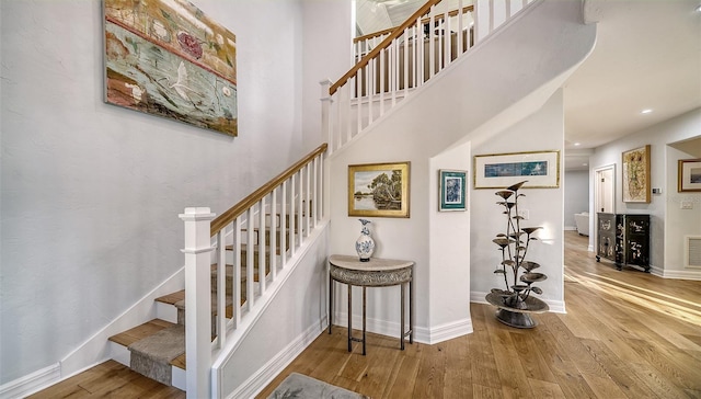 stairs with a towering ceiling and hardwood / wood-style floors