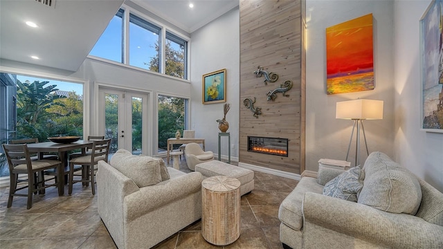 living room featuring a towering ceiling, a fireplace, and french doors