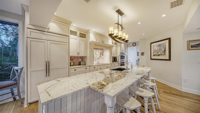 kitchen with a large island, light stone countertops, hanging light fixtures, and paneled built in refrigerator