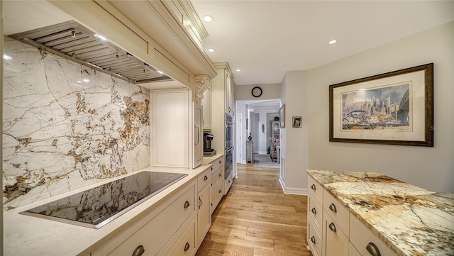 kitchen featuring custom exhaust hood, light stone counters, light wood-type flooring, black electric stovetop, and backsplash