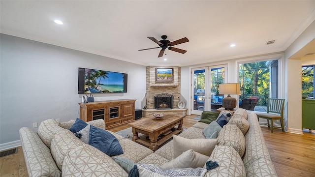 living room featuring french doors, crown molding, ceiling fan, a fireplace, and hardwood / wood-style floors