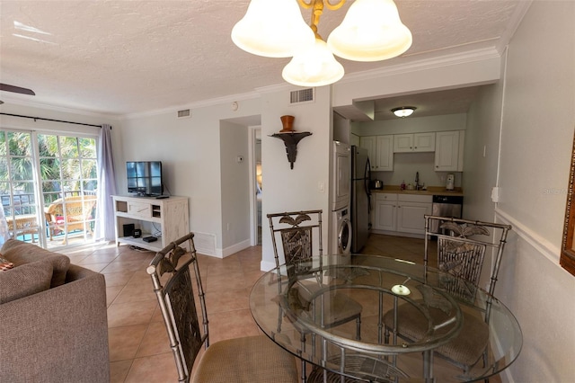 dining room with light tile floors, stacked washing maching and dryer, a textured ceiling, and ornamental molding