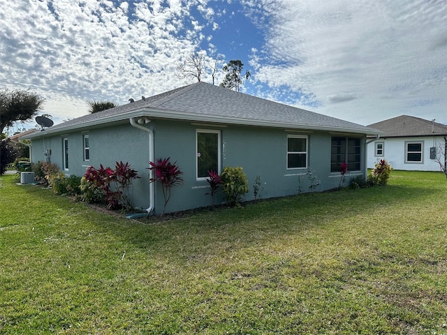 view of side of property featuring a lawn and central AC