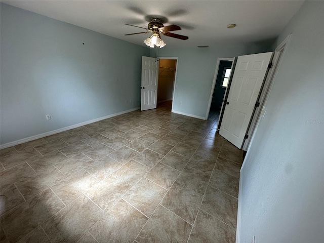 unfurnished bedroom with ceiling fan, a spacious closet, light tile floors, and a closet