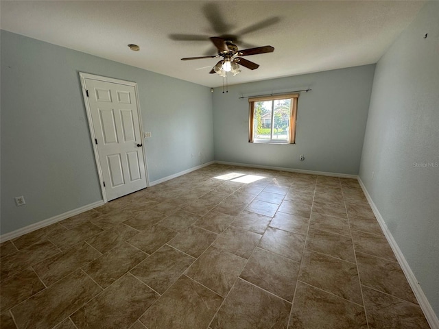 empty room with ceiling fan and dark tile floors