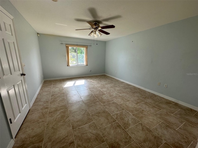 spare room featuring ceiling fan and dark tile flooring