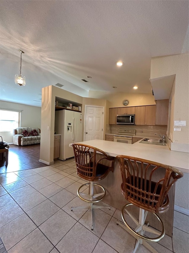 kitchen featuring an inviting chandelier, hanging light fixtures, a breakfast bar, white appliances, and sink