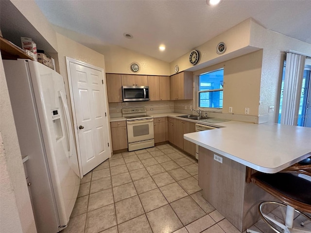 kitchen featuring a breakfast bar area, kitchen peninsula, white appliances, light tile flooring, and vaulted ceiling