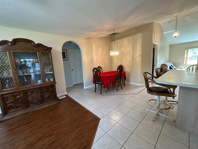 dining space with vaulted ceiling, light hardwood / wood-style flooring, a textured ceiling, and an inviting chandelier