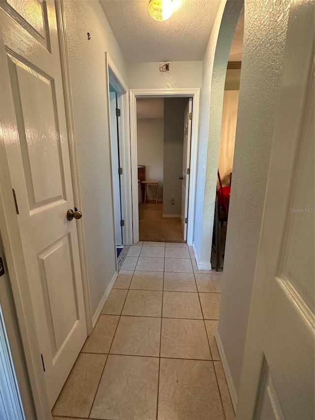 hallway with light tile flooring and a textured ceiling