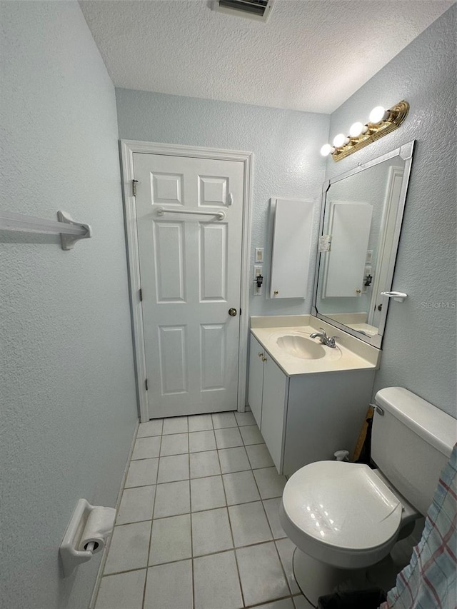 bathroom with tile floors, toilet, a textured ceiling, and vanity