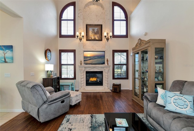 living room featuring dark hardwood / wood-style floors, a towering ceiling, and a fireplace