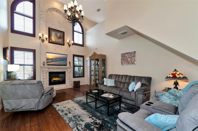 living room featuring a large fireplace, a high ceiling, dark hardwood / wood-style floors, and an inviting chandelier