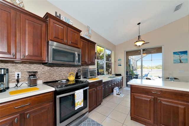 kitchen featuring stainless steel appliances, decorative light fixtures, light tile floors, vaulted ceiling, and tasteful backsplash