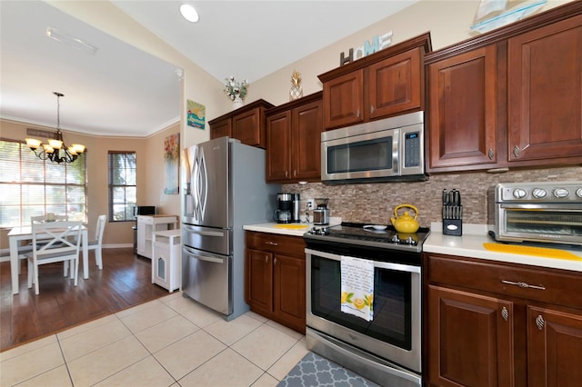 kitchen with backsplash, a notable chandelier, appliances with stainless steel finishes, and light tile floors