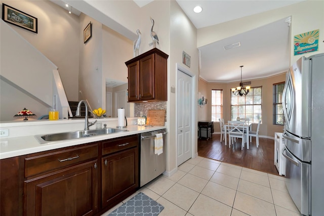 kitchen with pendant lighting, light tile floors, sink, appliances with stainless steel finishes, and an inviting chandelier