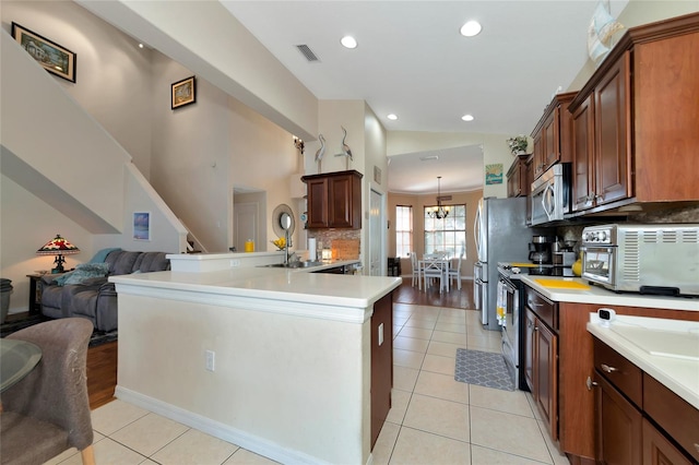 kitchen with light tile flooring, backsplash, stainless steel appliances, and a notable chandelier