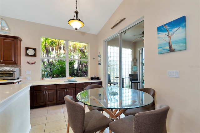 dining room featuring ceiling fan, light tile floors, and lofted ceiling