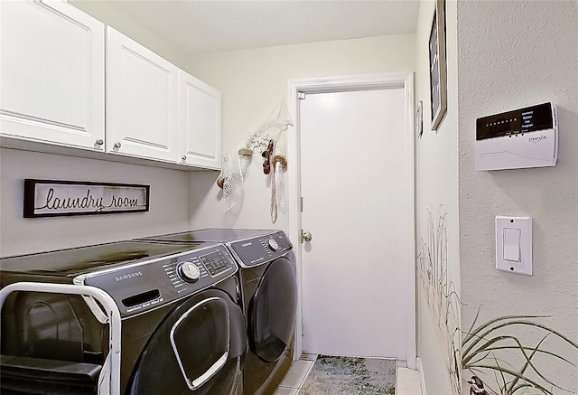 laundry area with light tile flooring, washing machine and dryer, and cabinets