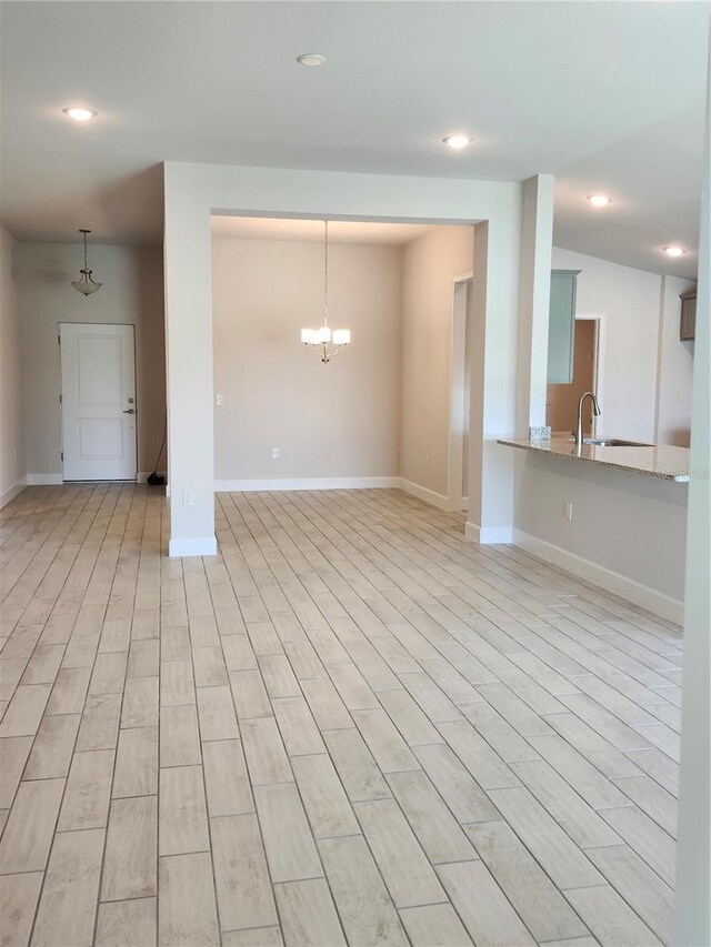 unfurnished living room with sink and a chandelier