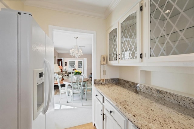 kitchen with white refrigerator with ice dispenser, a chandelier, white cabinetry, and light stone countertops